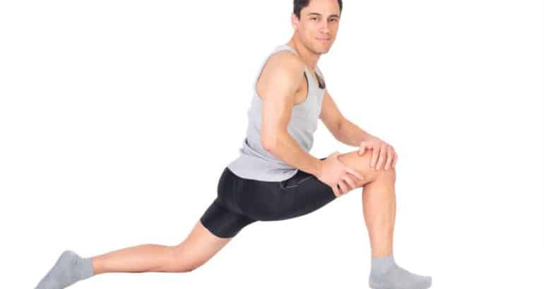 Positive sportsman doing stretching exercise in studio